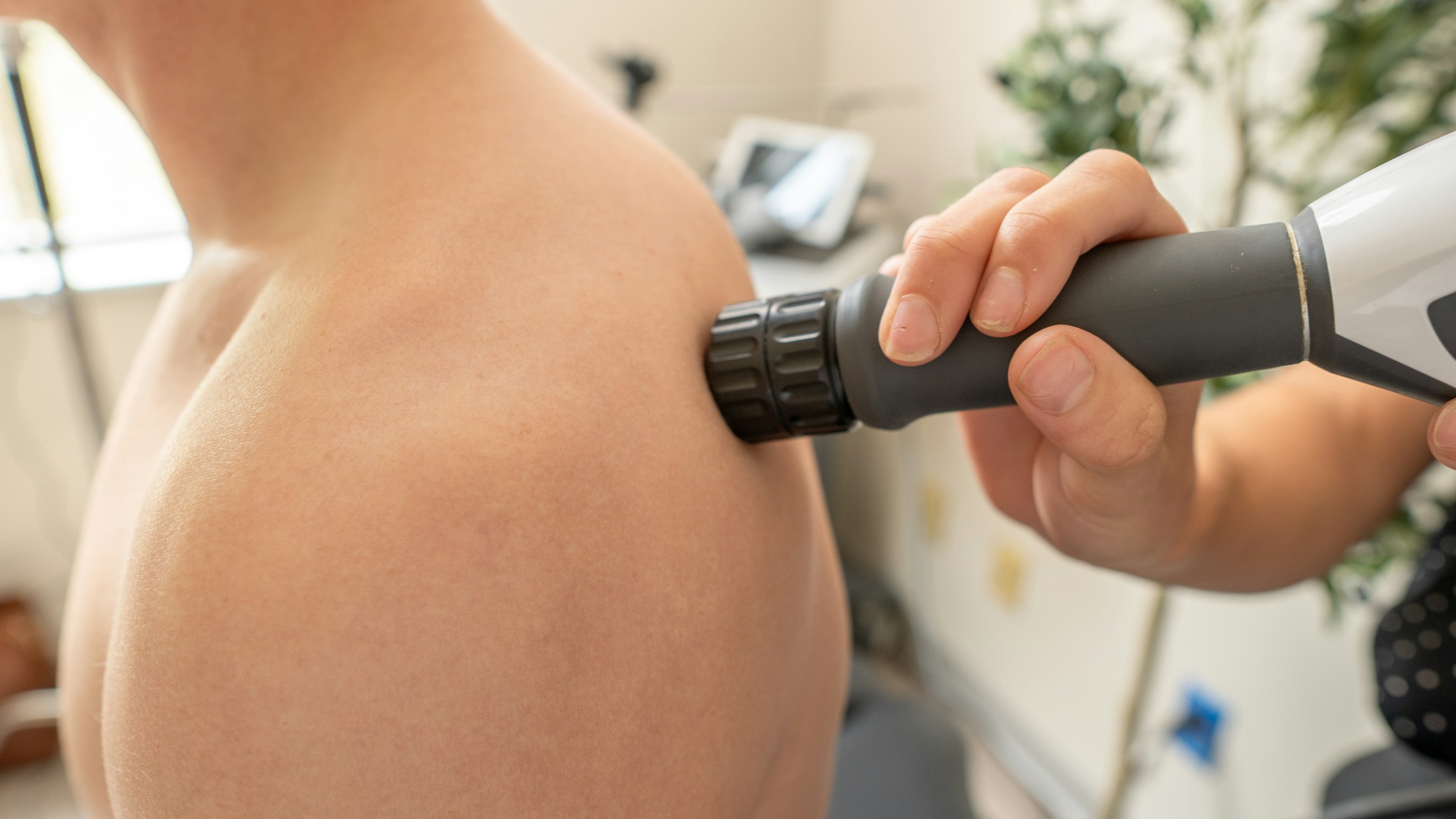 Radial shockwave therapy being applied to a patient's shoulder at Glasgow Sport & Spine Clinic